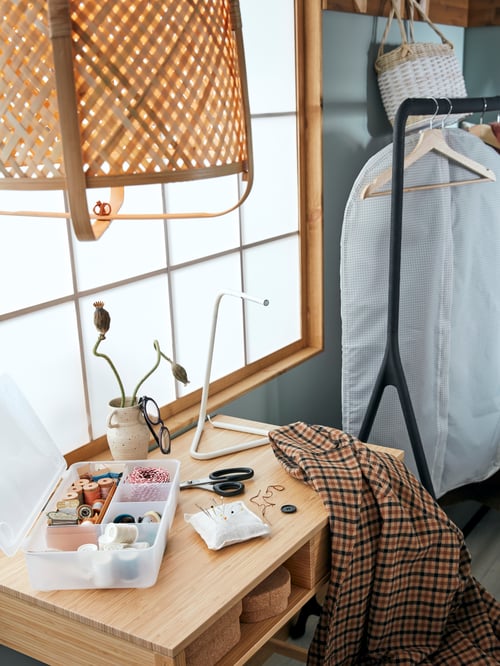 Bedroom with desk, clothes rack, hangers, clothes, pendant lamp, boxes with lids, plastic box, sewing accessories, reading lamp.
