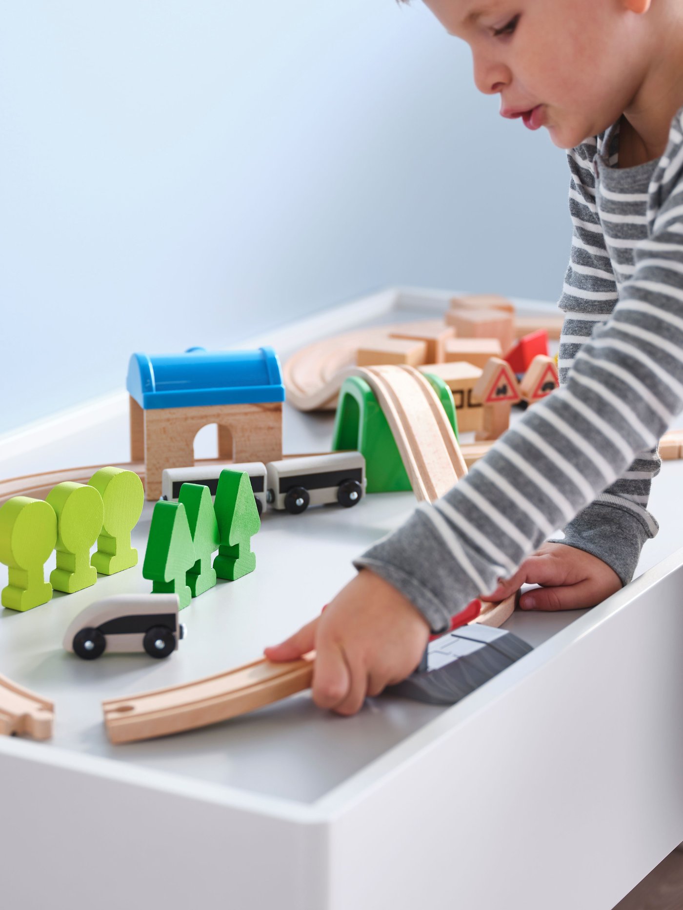 A child playing with a LILLABO track set and trains.