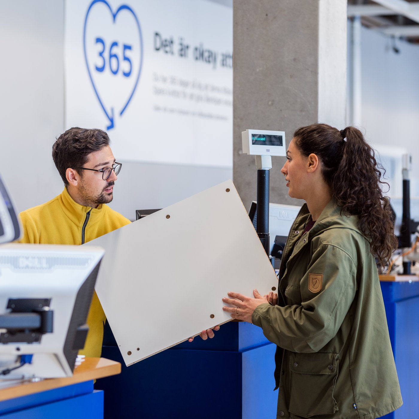 Kobieta zwraca produkt w sklepie IKEA. Pracownik IKEA przyjmuje zwrot.