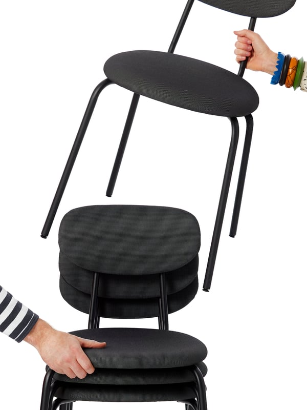 Stapel med gråa stolar där en person lyfter upp en stol. 