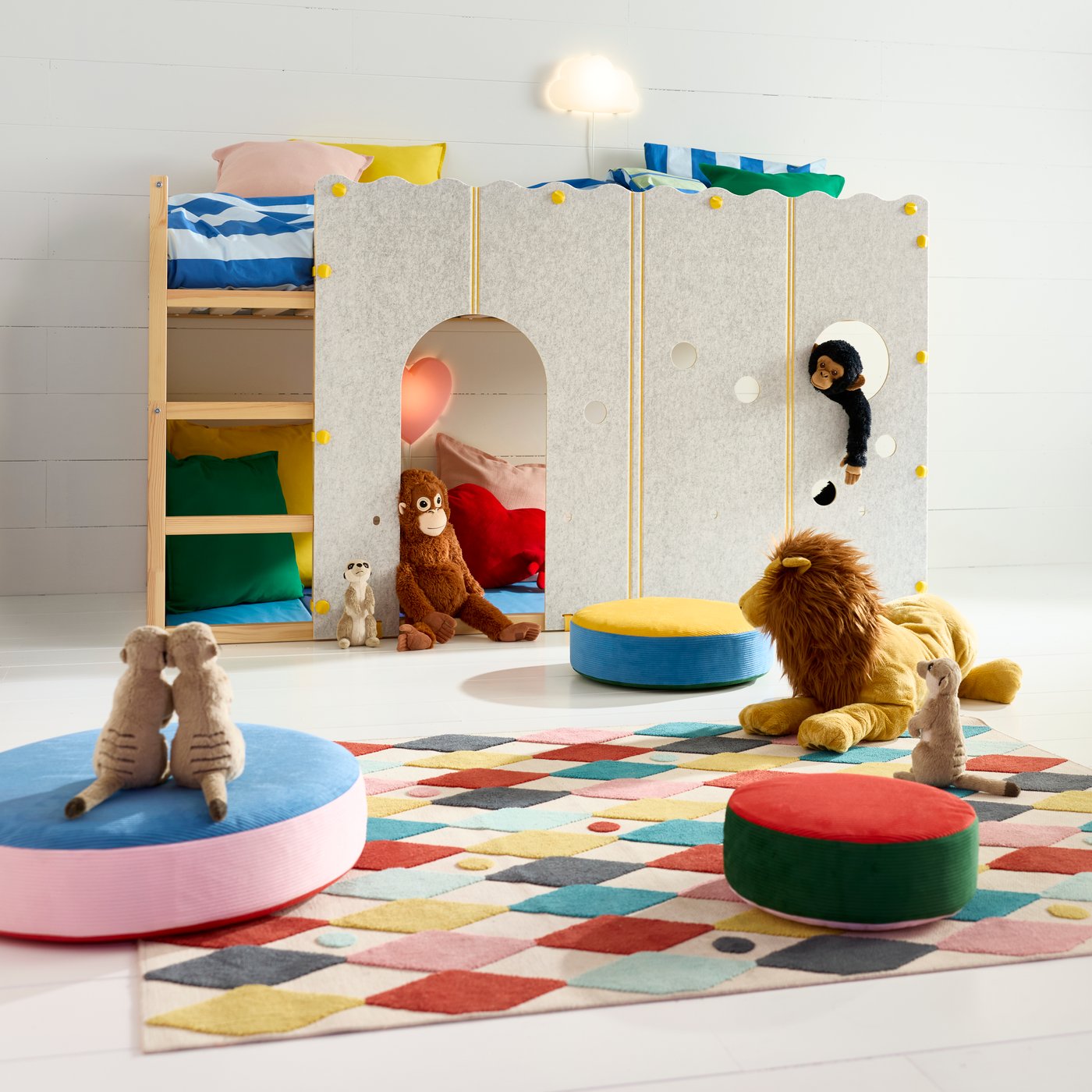 A KURA bed accessory attached to a KURA reversible bed in a children’s room furnished with cushions, rugs and toys.
