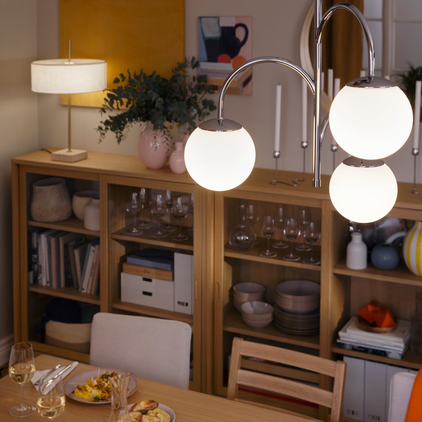 A dining room with a SIMRISHAMN ceiling lamp hanging over a TONSTAD dining table and a STOCKHOLM table lamp on a cabinet.