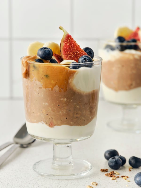 Two cups of overnight muesli with berries and fruit on the top.