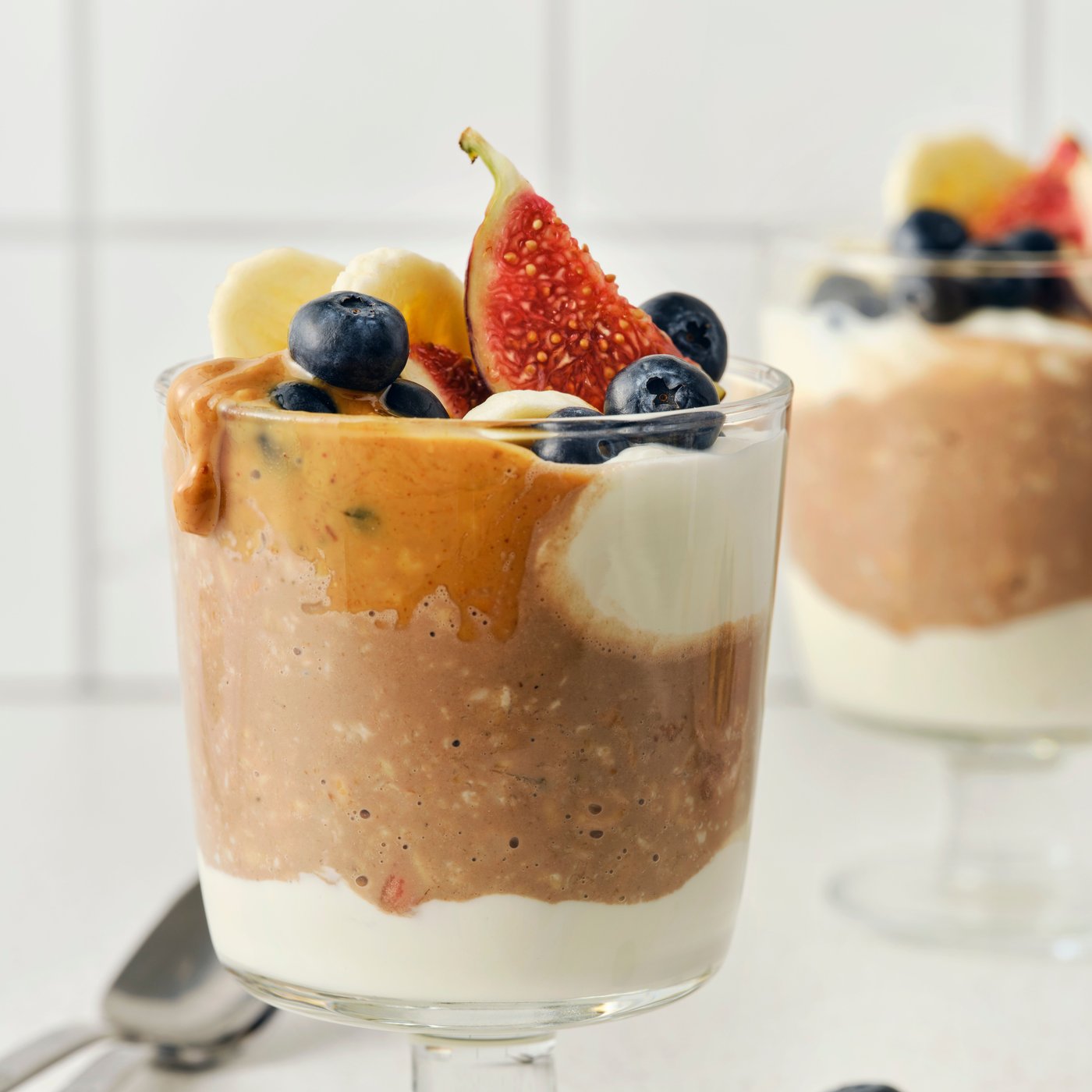 Two cups of overnight muesli with berries and fruit on the top.