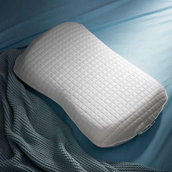 A KLUBBSPORRE cooling ergonomic pillow placed on a light blue bedsheet.