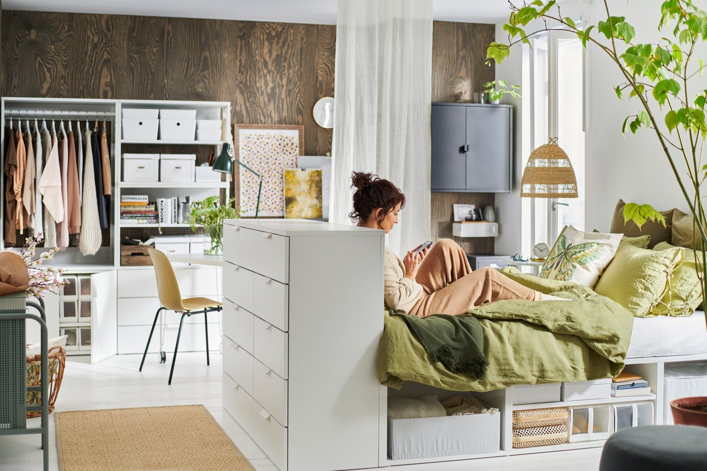 Eine Frau sitzt auf einem Bett und tippt auf ihrem Smartphone.