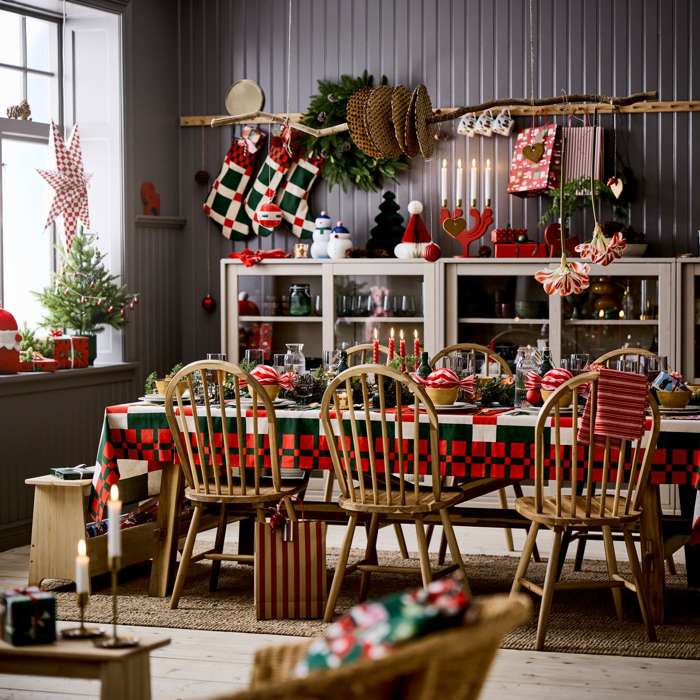 An IKEA SKOGSTA dining table in acacia wood dressed for Christmas and six matching SKOGSTA chairs in a room with dark grey walls.