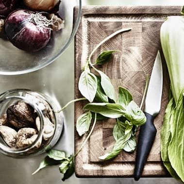 Grünes Gemüse und Pflücksalate auf einem Schneidebrett aus Holz