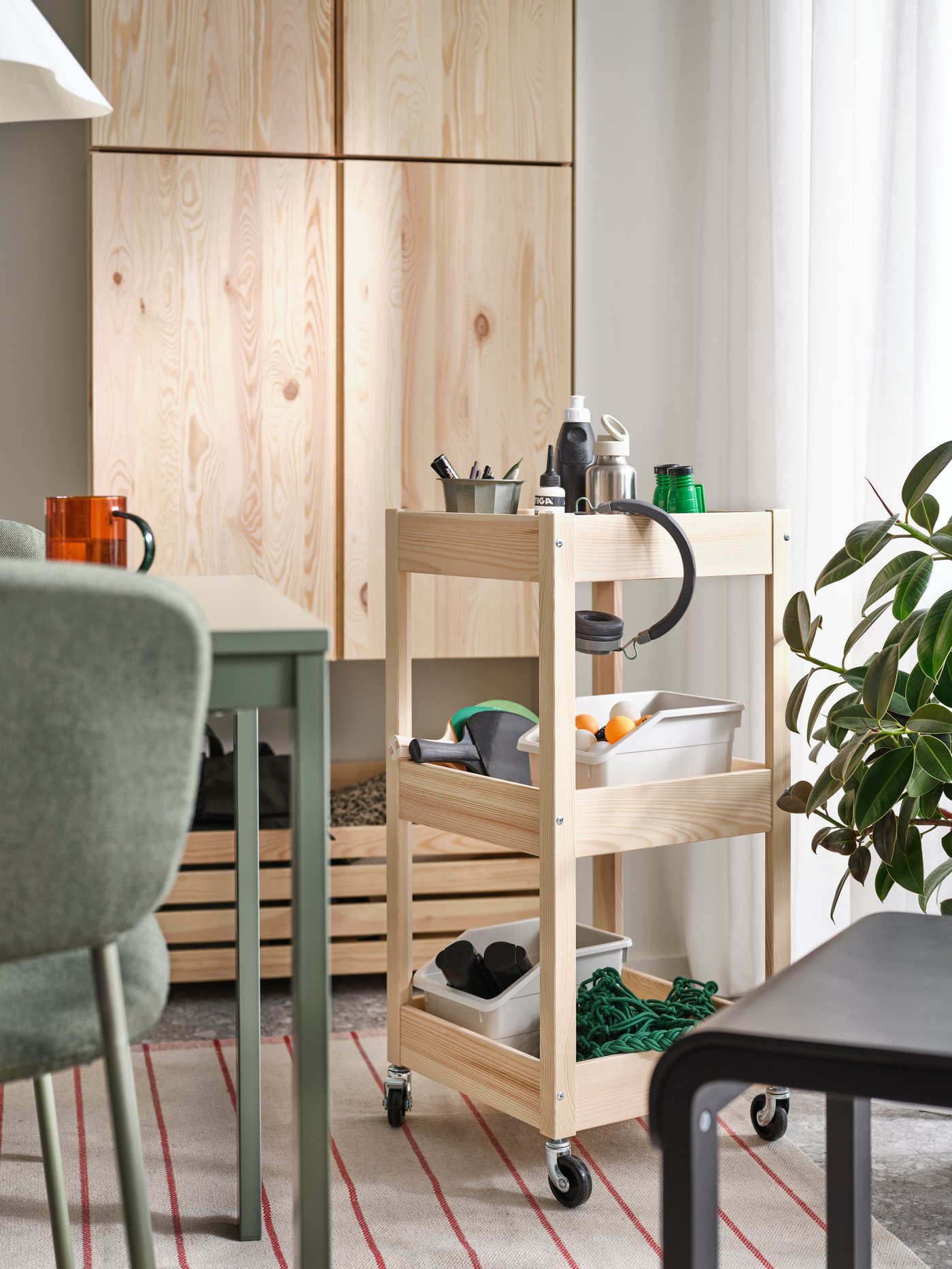 A LOSHULT trolley stands on a RIDSTIG rug in a multifunctional dining room next to two IVAR cabinets on the wall.