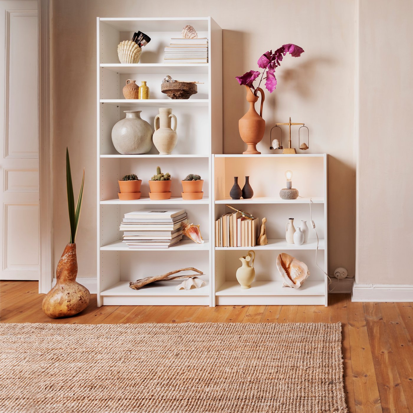 Two BILLY bookcases in an empty hallway displaying decorative items such as vases, books and other figurines. 