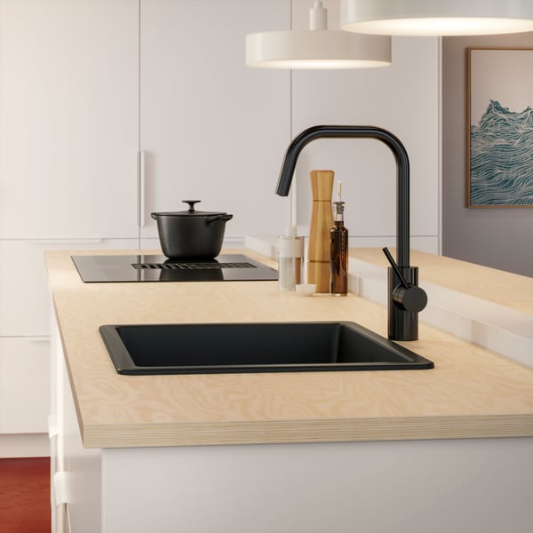 A kitchen sink area with an EKBACKEN worktop in plywood effect laminate, a VARDAGEN pot and an ÄLMAREN mixer tap in black.