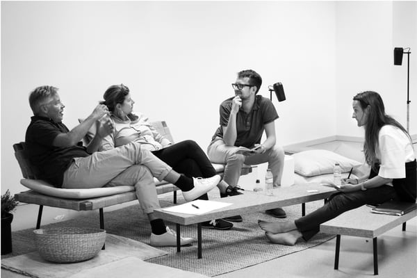 Four people is sitting in a office lounge area having an informal meeting.
