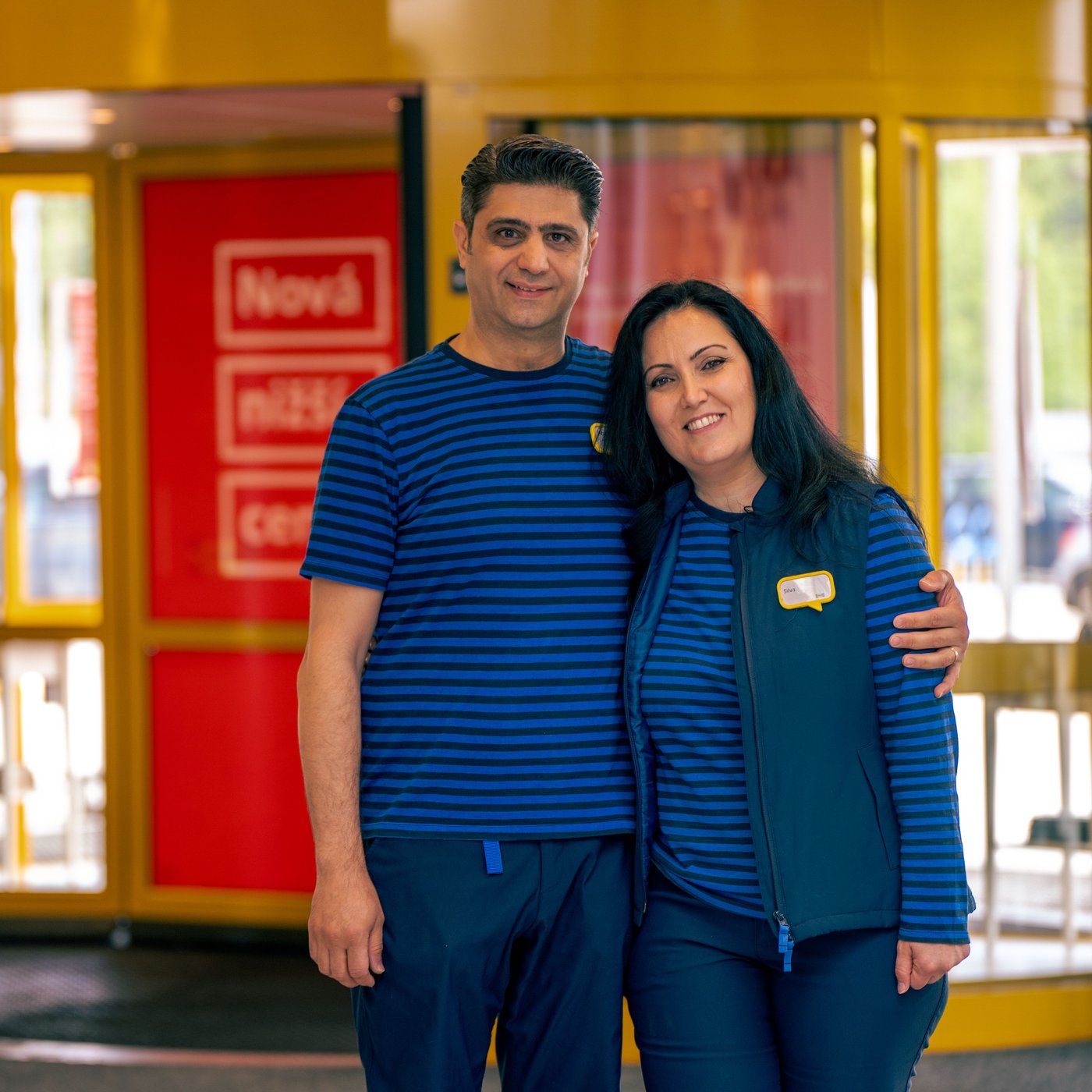 Silva and Abdul in their blue IKEA work uniforms holding each other.