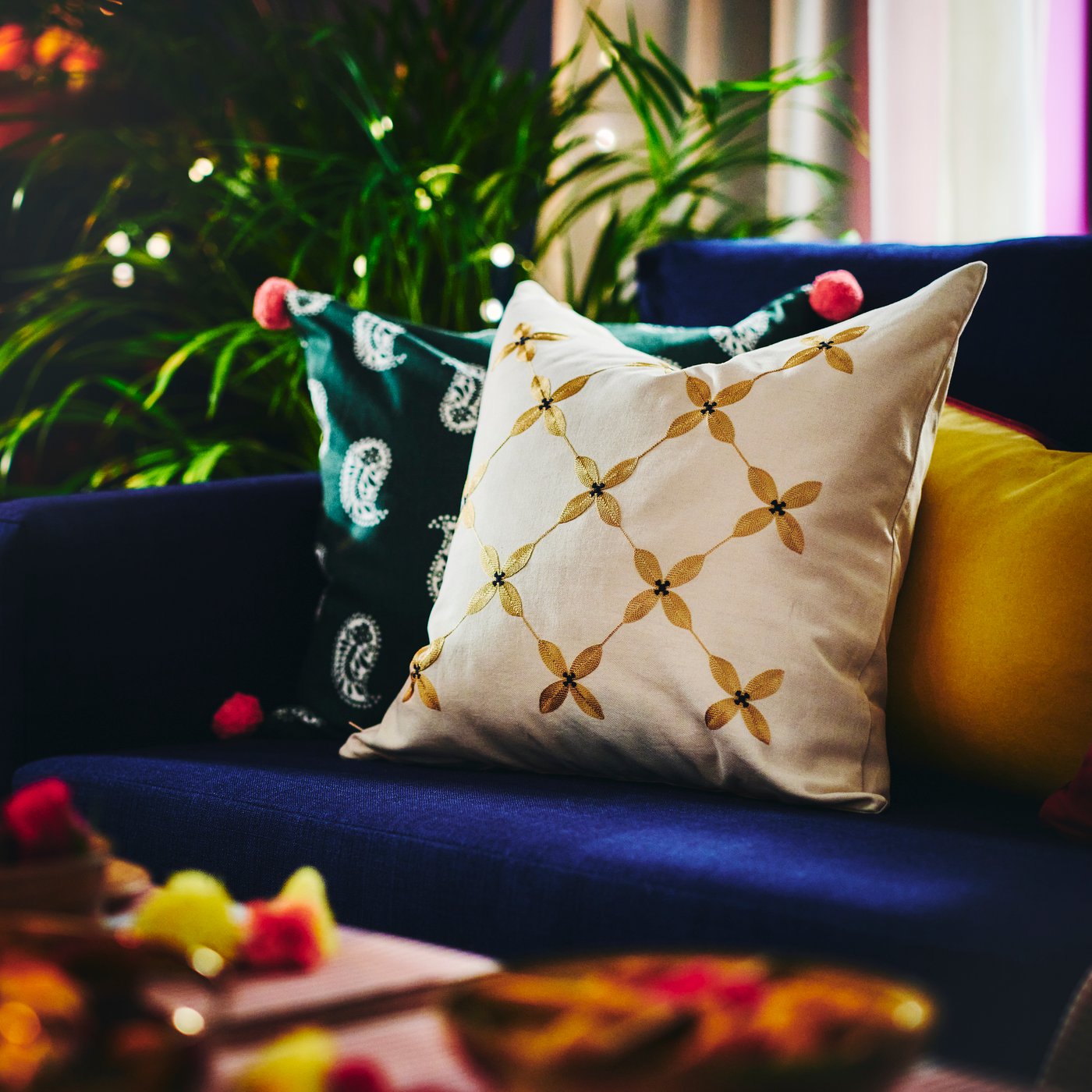 AROMATISK beige pillow sitting on blue sofa.