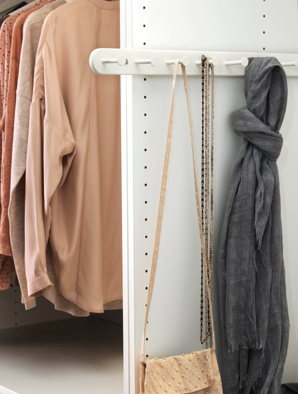 KOMPLEMENT pull-out multi-use hanger with bags and beaded necklaces.