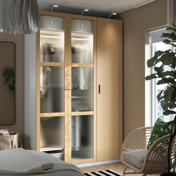 A white/oak veneer glass PAX wardrobe combination in the bedroom