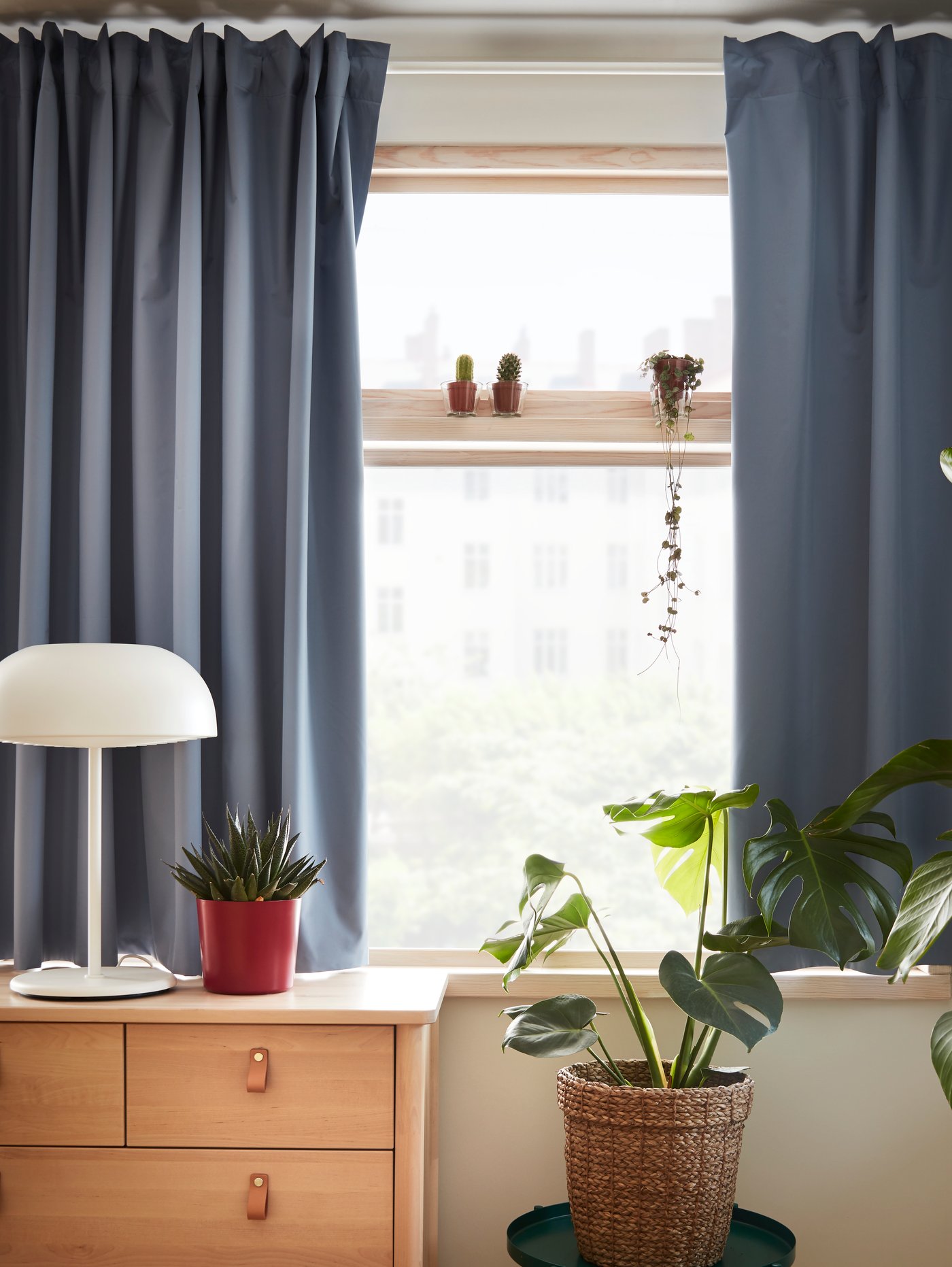 Cortina blackout azul BENGTA en las ventanas de undormitorio detrás de una cómoda.