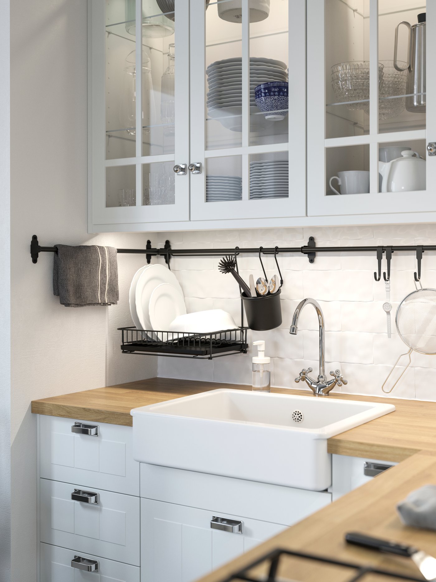 Cocina con varios armarios de pared con puertas de vidrio, debajo de los cuales hay unos platos en un escurreplatos colgados de un riel.