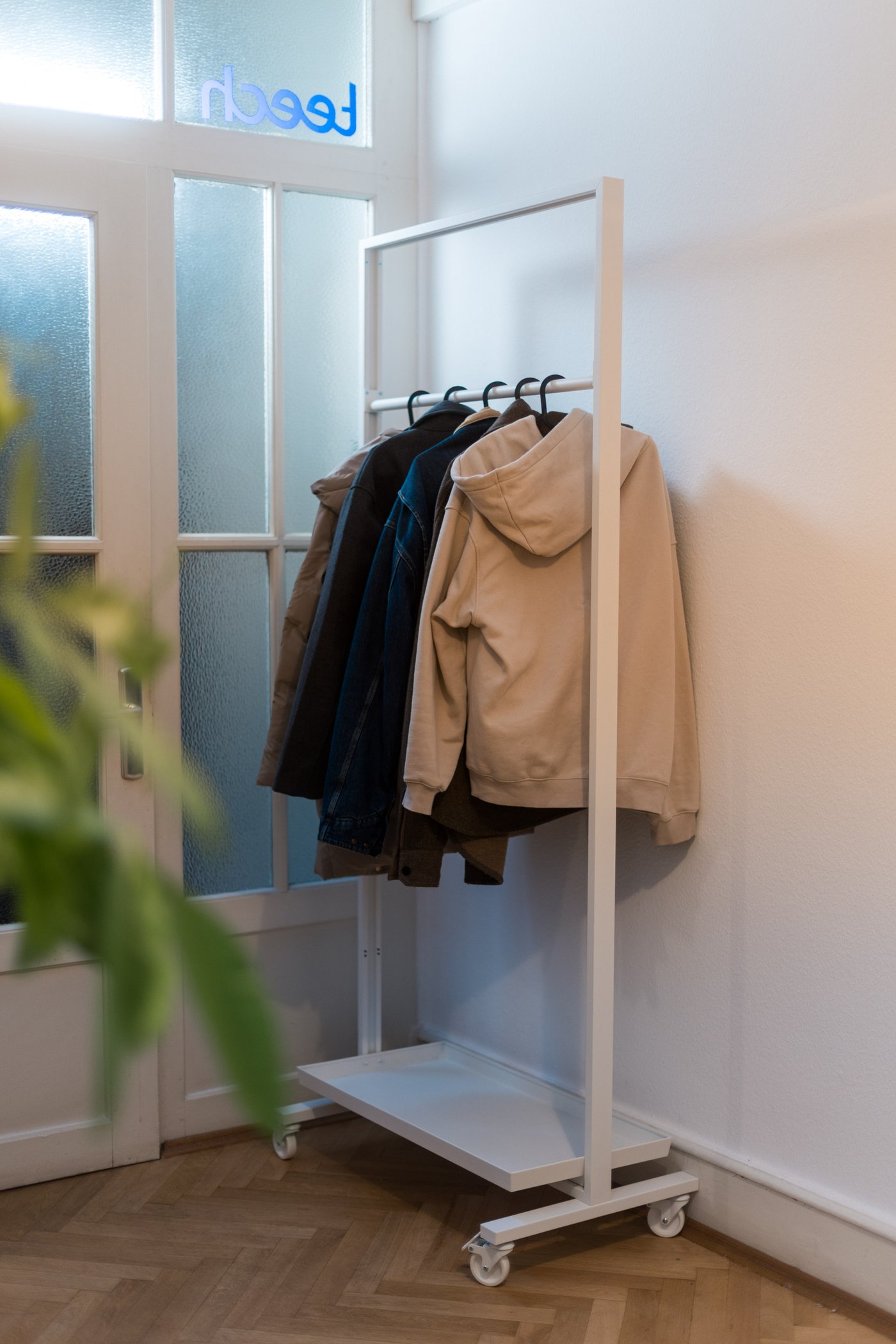 Offene Garderobe mit mehreren aufgehängten Jacken in einem hellen Eingangs- oder Arbeitsbereich.