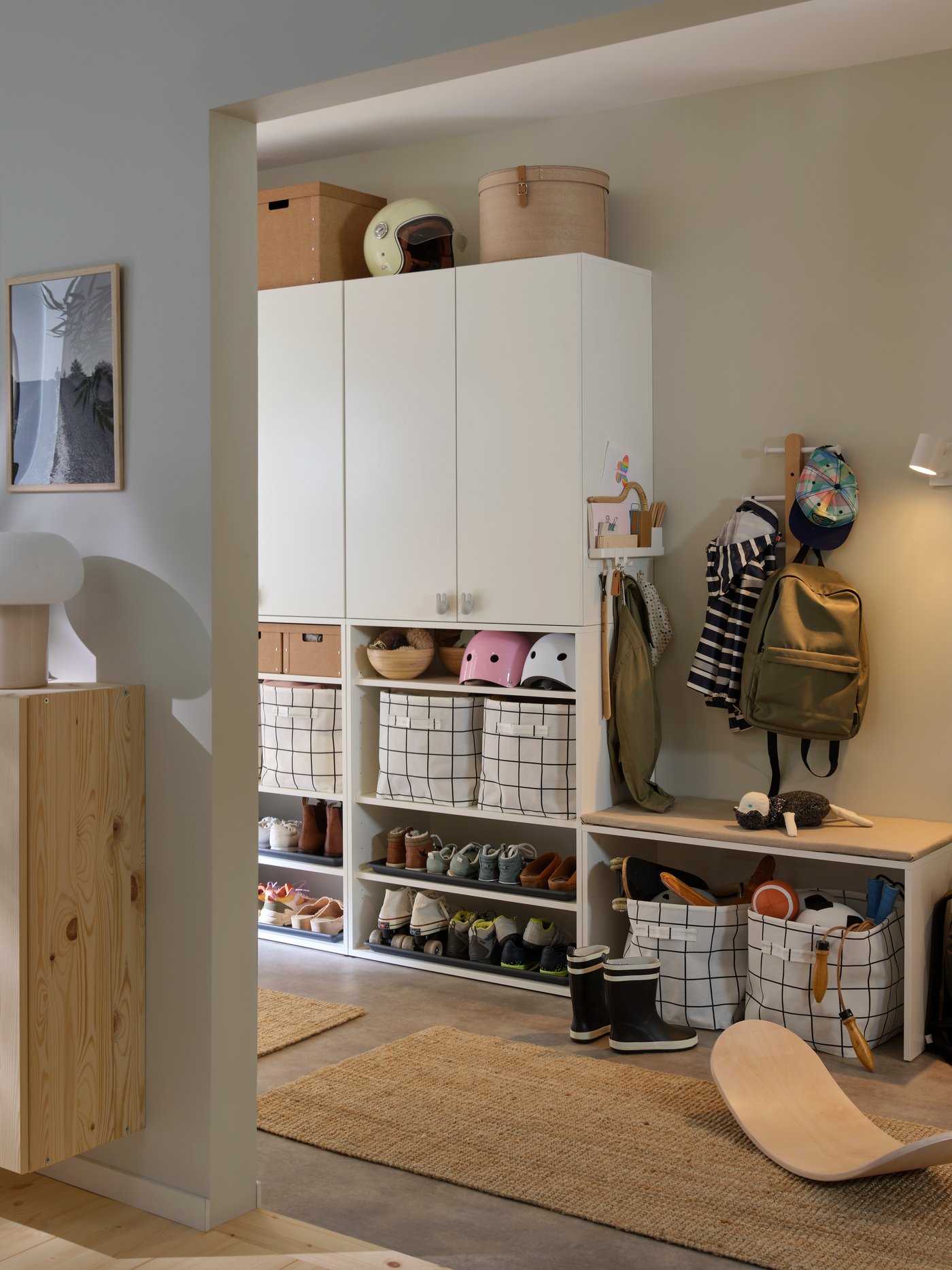 A hallway with LASTARE wardrobe combinations showing closed cabinets above and baskets stored on open shelves.