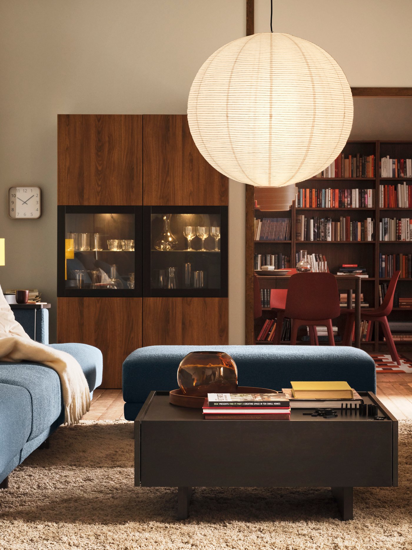 A TRANERED coffee table stands in front of an UPPÅKRA 4.5-seat modular sofa near a BESTÅ storage combination with glass doors.
