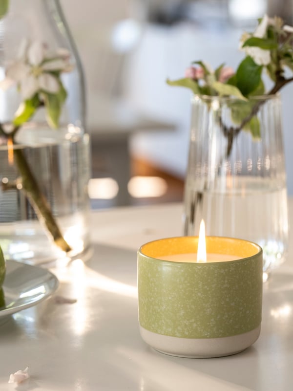 An Apple/bright beige-yellow LÖVSKOGSLUND scented candle in ceramic jar