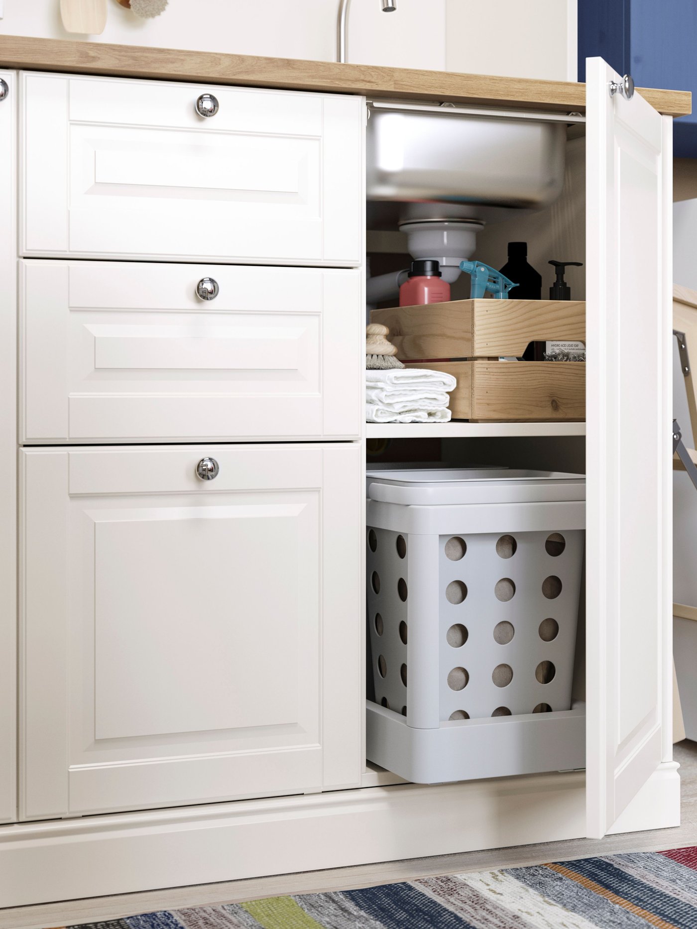 Interior d’un moble de cuina amb una caixa perforada i una safata amb productes de neteja.