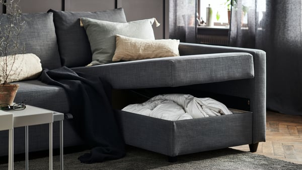 En mørkegrå FRIHETEN sovesofa i en stue med oppbavering under setet.