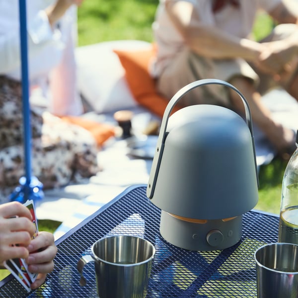 The VAPPABY Bluetooth speaker lamp sits on a table in the park, providing music for the picnic.