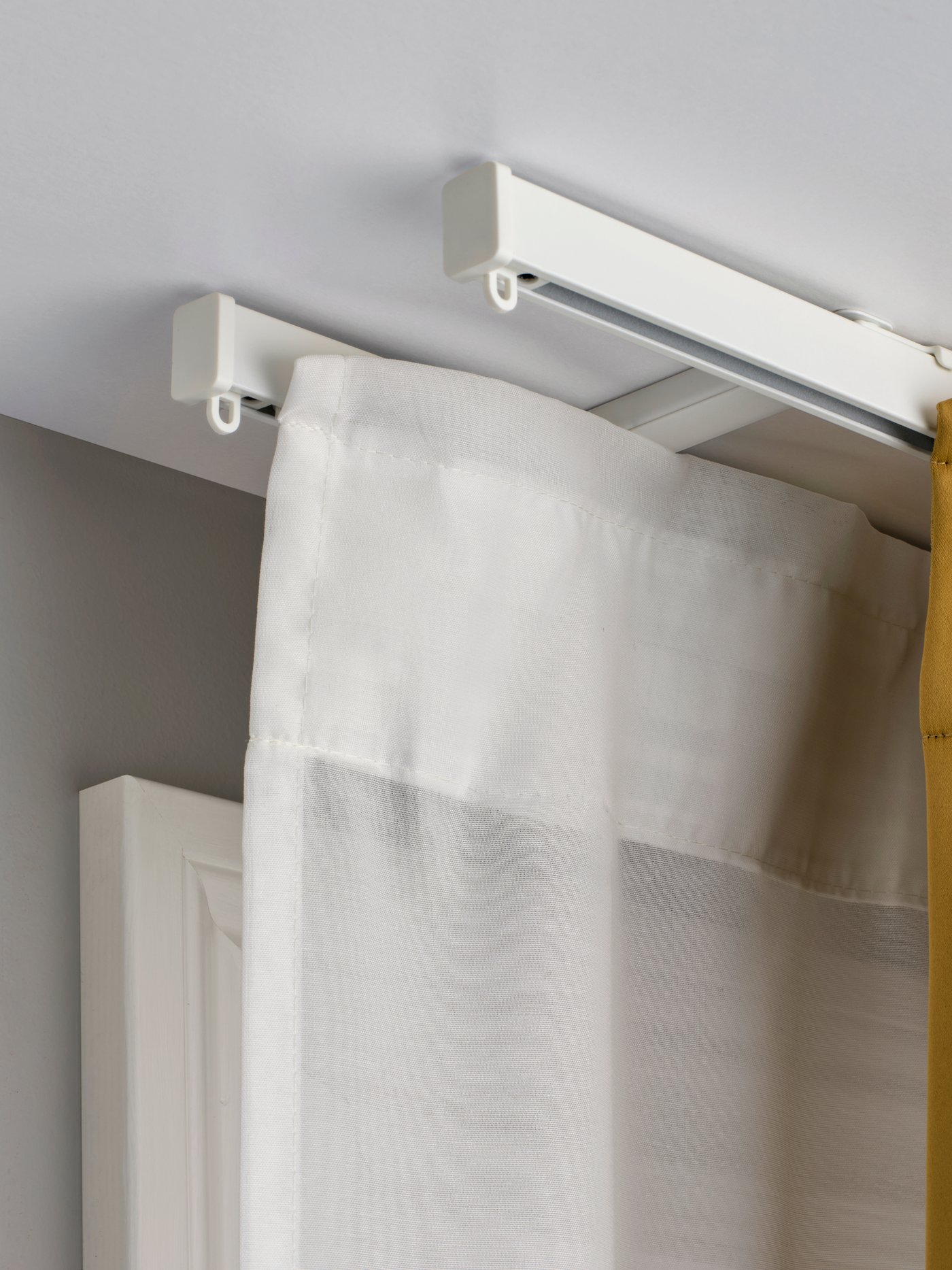 A white VIDGA ceiling bracket for 2 curtain rails