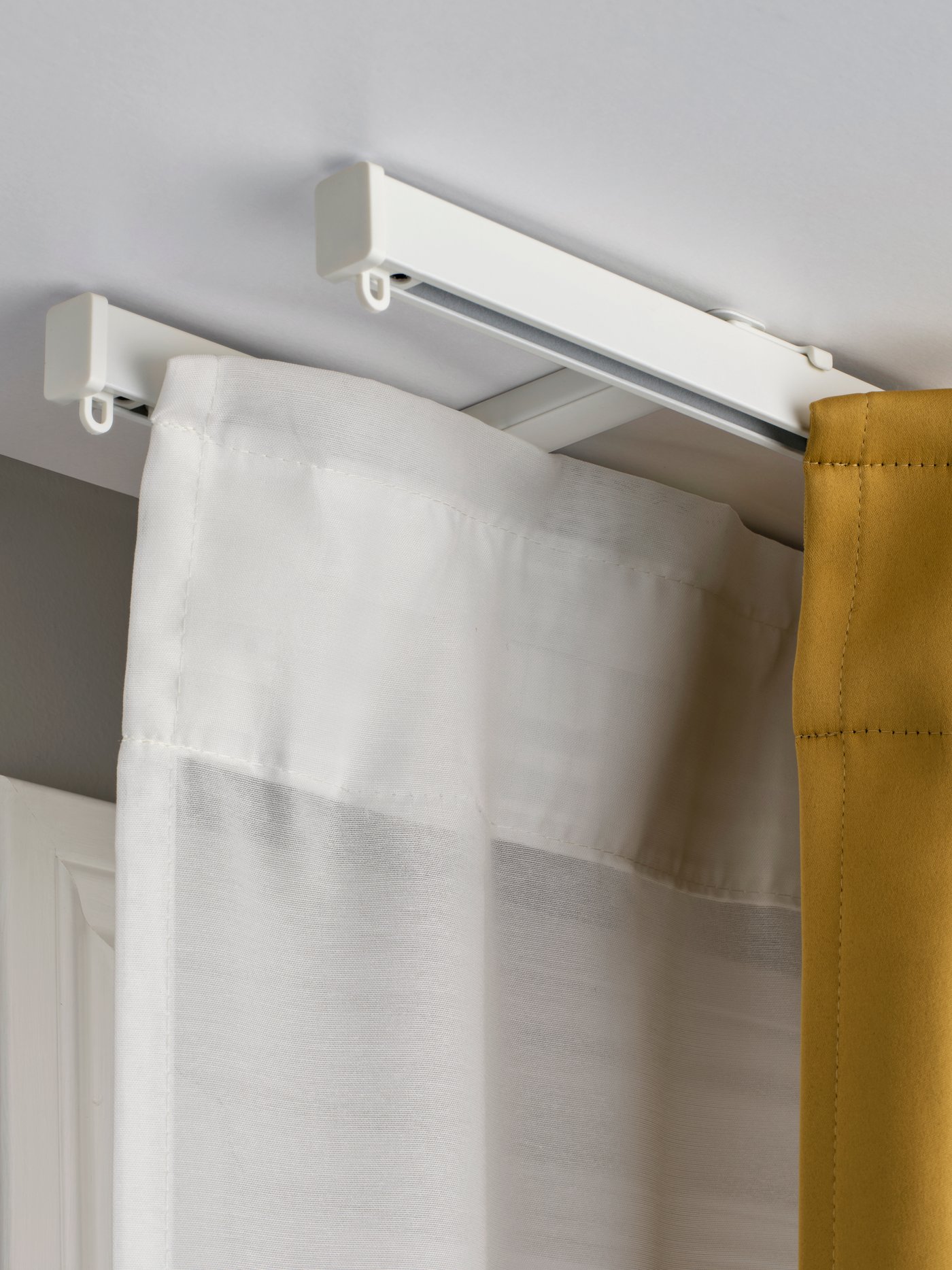 A white VIDGA ceiling bracket for 2 curtain rails