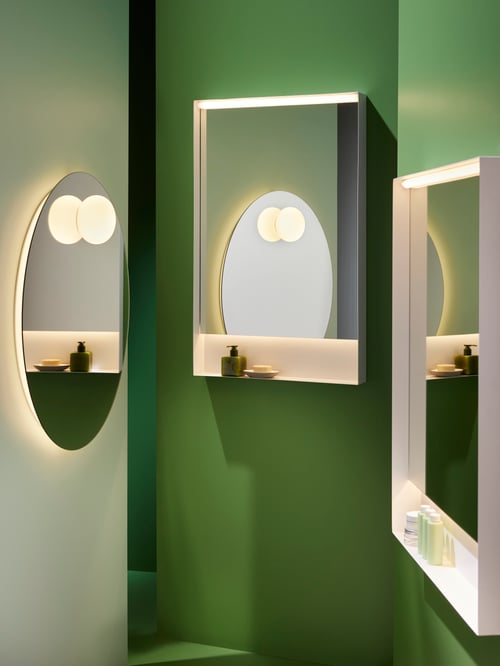 O baie cu două oglinzi pătrate FAXÄLVEN iluminate, cu iluminat încorporat și o oglindă rotundă iluminată, cu iluminat.