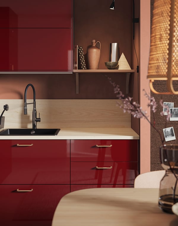 Partial view of a red kitchen with shiny fronts with sink and wall cabinets above