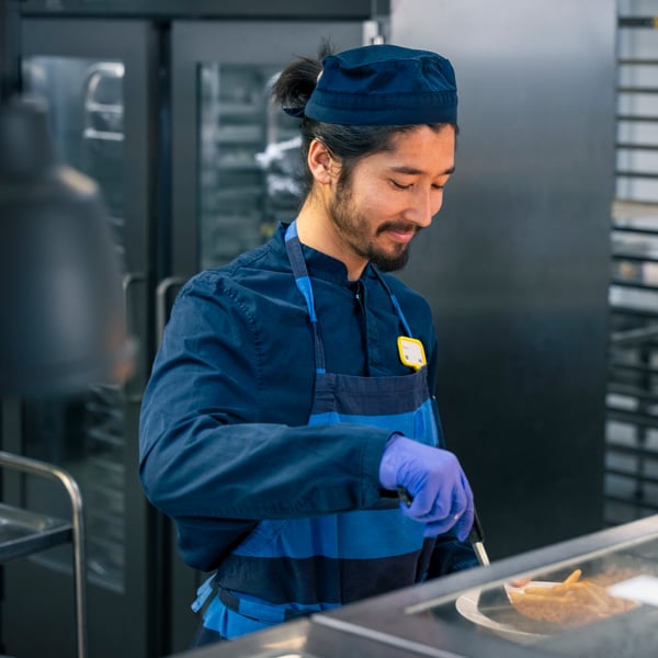 A smiling IKEA co-worker wearing blue workwear and a name badge.