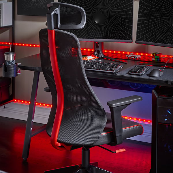 An IKEA MATCHSPEL gaming chair in black and red in front of a black gaming desk lit with red neon lights.