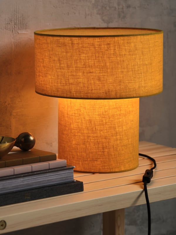 A STOCKHOLM 2025 table lamp on a sideboard in the living room.