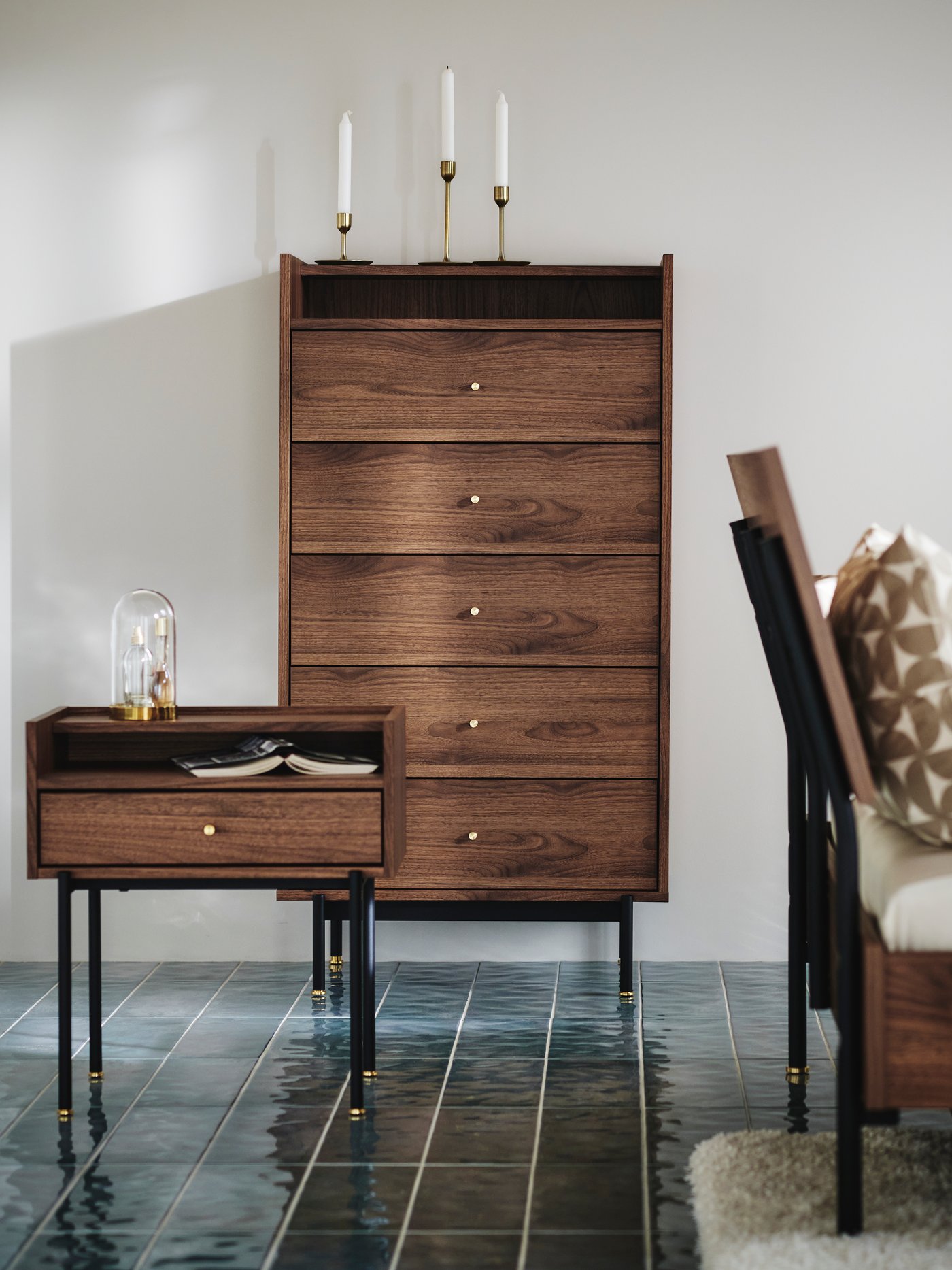 The RÅDMANSÖ series presented with a bedside table and a chest of 5 drawers, standing in a bedroom with blue floor.