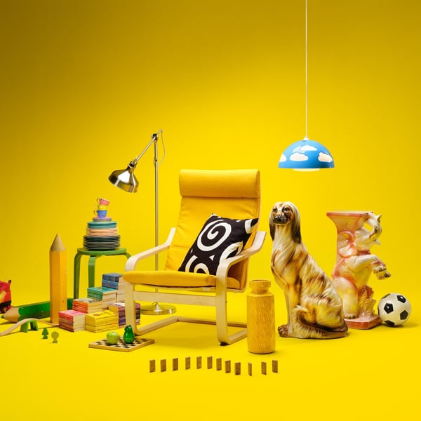 Färgstark studiobild med ett gult tema: en gul fåtölj, leksaker, en lampa och dekorationer placerade mot en helgul bakgrund.