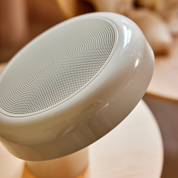 A close-up of the top of a BLOMPRAKT Bluetooth speaker lamp standing on top of a STOCKHOLM 2025 side table.