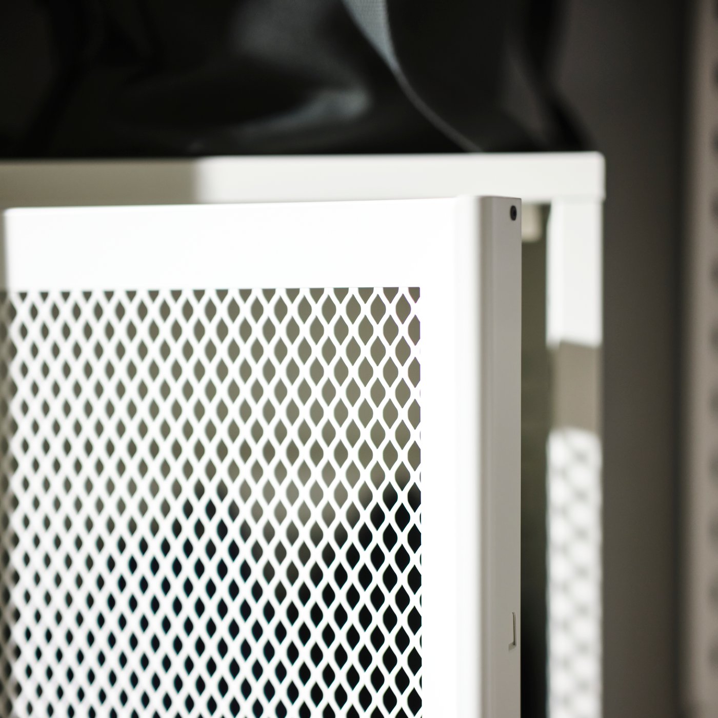 A close-up of the slightly ajar door of a white mesh IVAR cabinet.