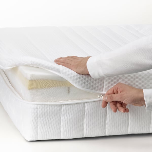 a close up shot of a person unzipping a mattress cover off a foam mattress