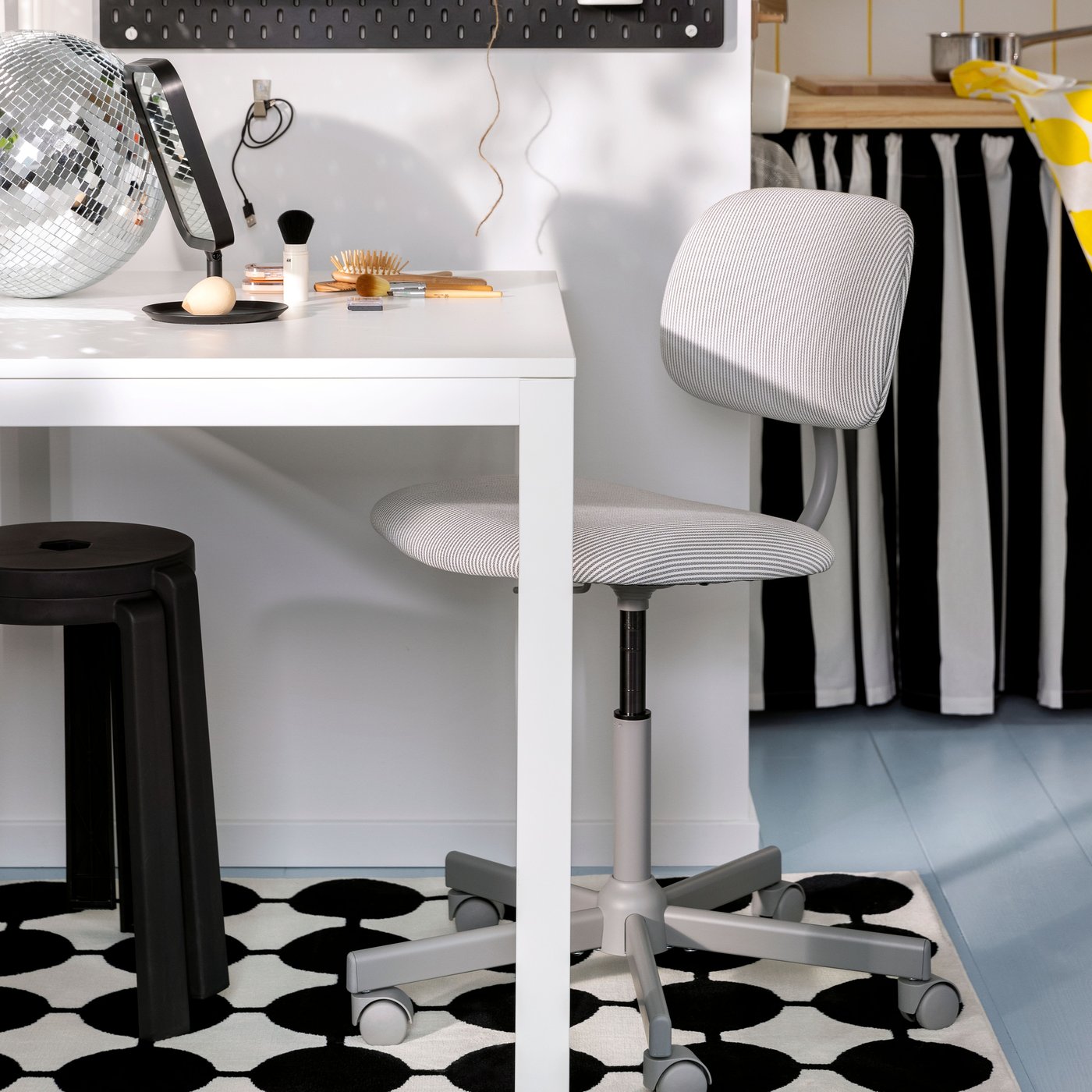 En BLECKBERGET snurrstol står vid ett VIHALS utdragbart bord som har en LINDBYN bordsspegel och en discokula ovanpå.