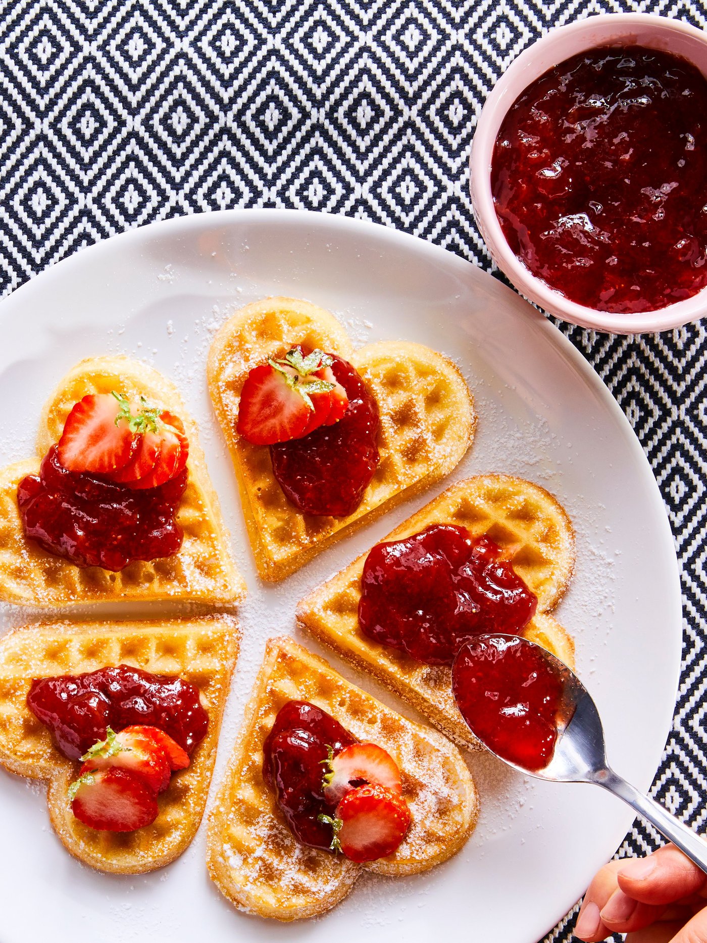 Waffeln werden mit Marmelade und frischen Erdbeeren belegt