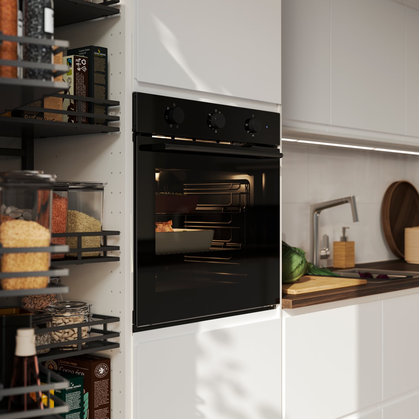 A black SPJUTBO fan oven is placed in a kitchen with matt white VOXTORP fronts and there’s food baking inside.