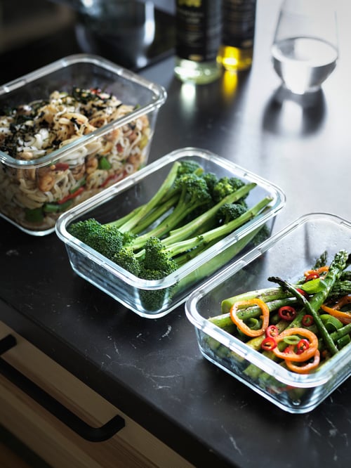 Set bucatarie oferind un focalizat împușcat de trei containere alimentare, fiecare conținând diferite legume și alte produse alimentare.