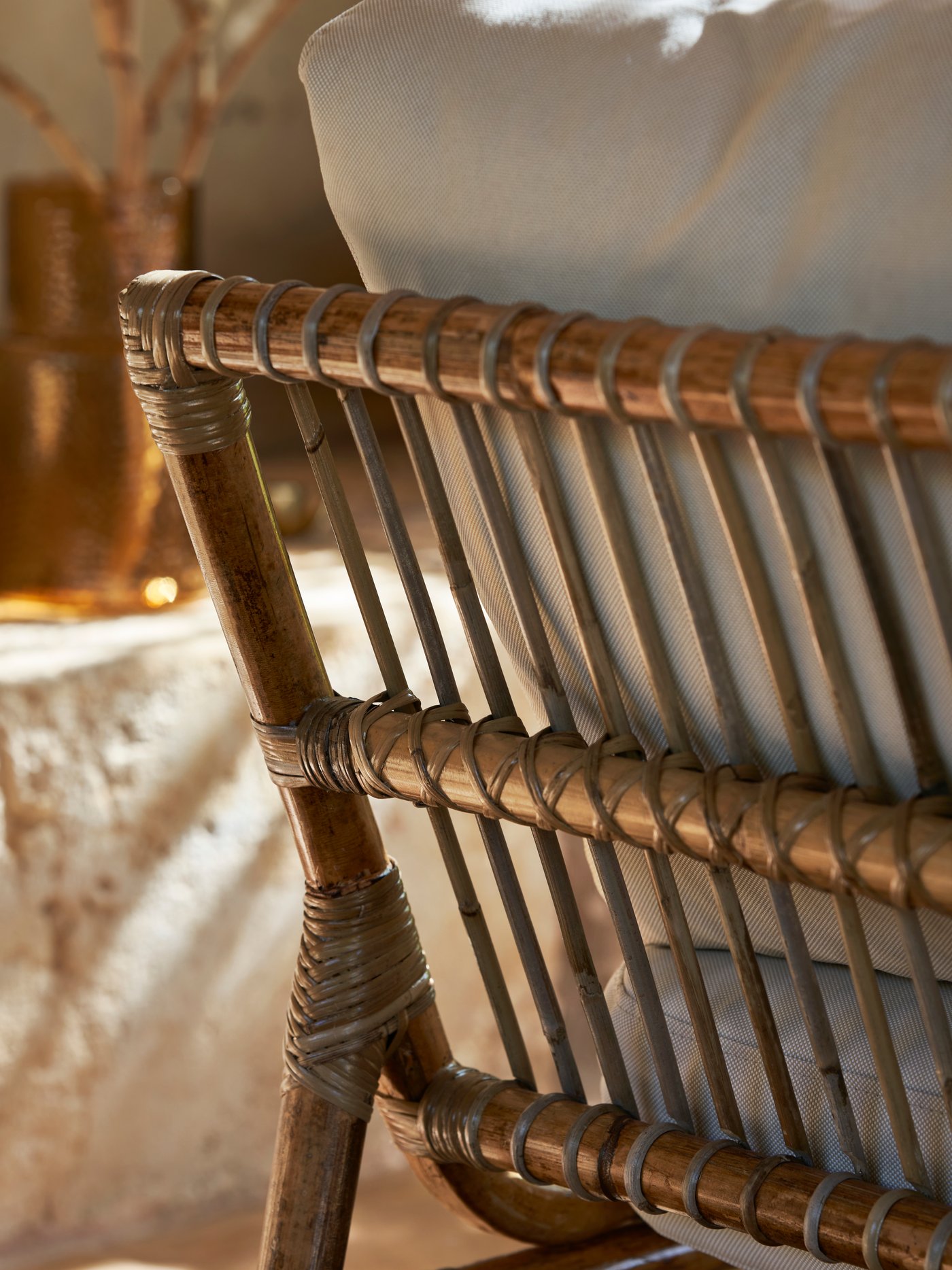 Rottingfåtölj med en ljus kudde.