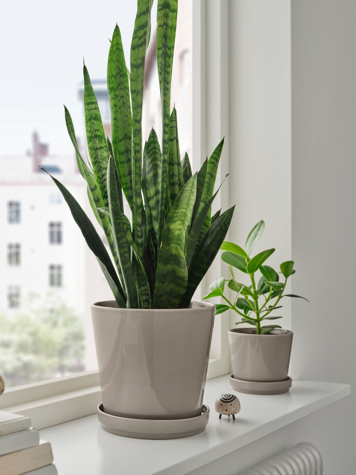 Een grijs/beige KLOTLÖNN plantenpot met schotel