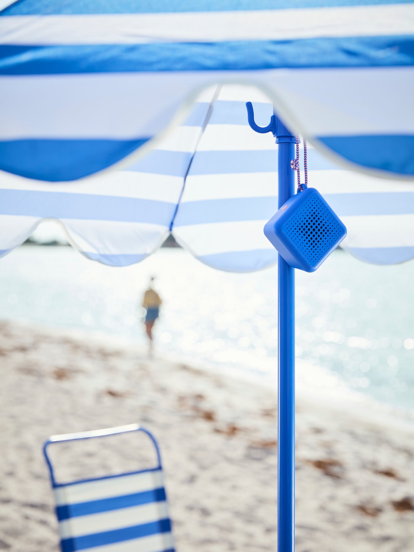 VAPPEBY blue bluetooth speaker hanging in a parasol at the beach.