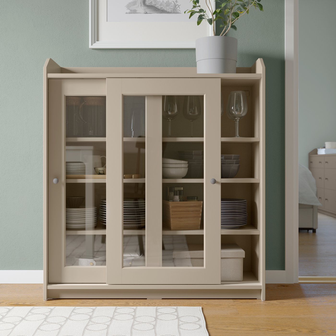 A beige HAUGA glass-door cabinet in the dining room