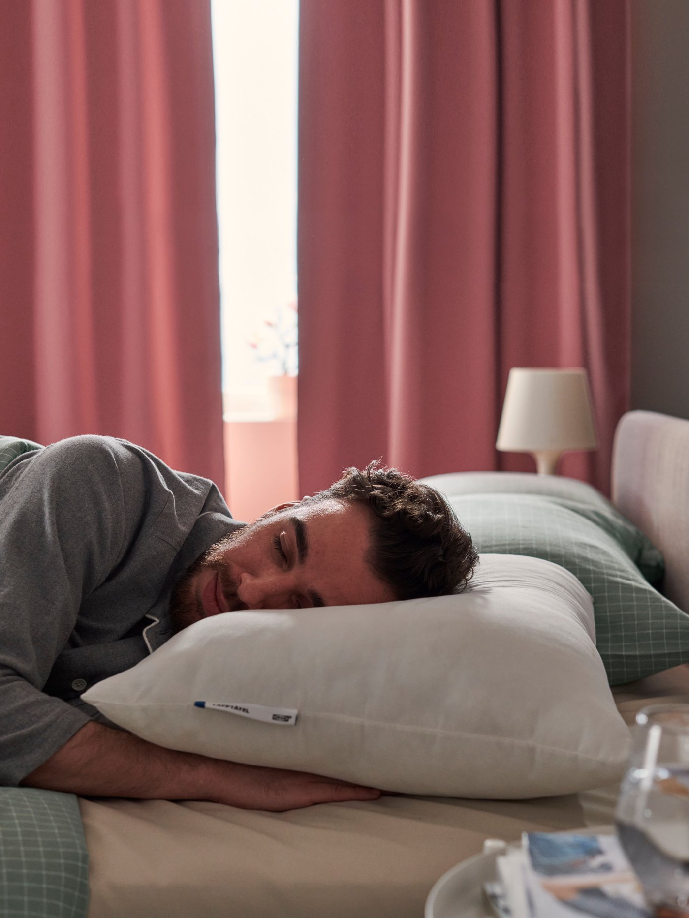 Un hombre recostado en una cama y su cabeza sobre una almohada LAPPTÅTEL 